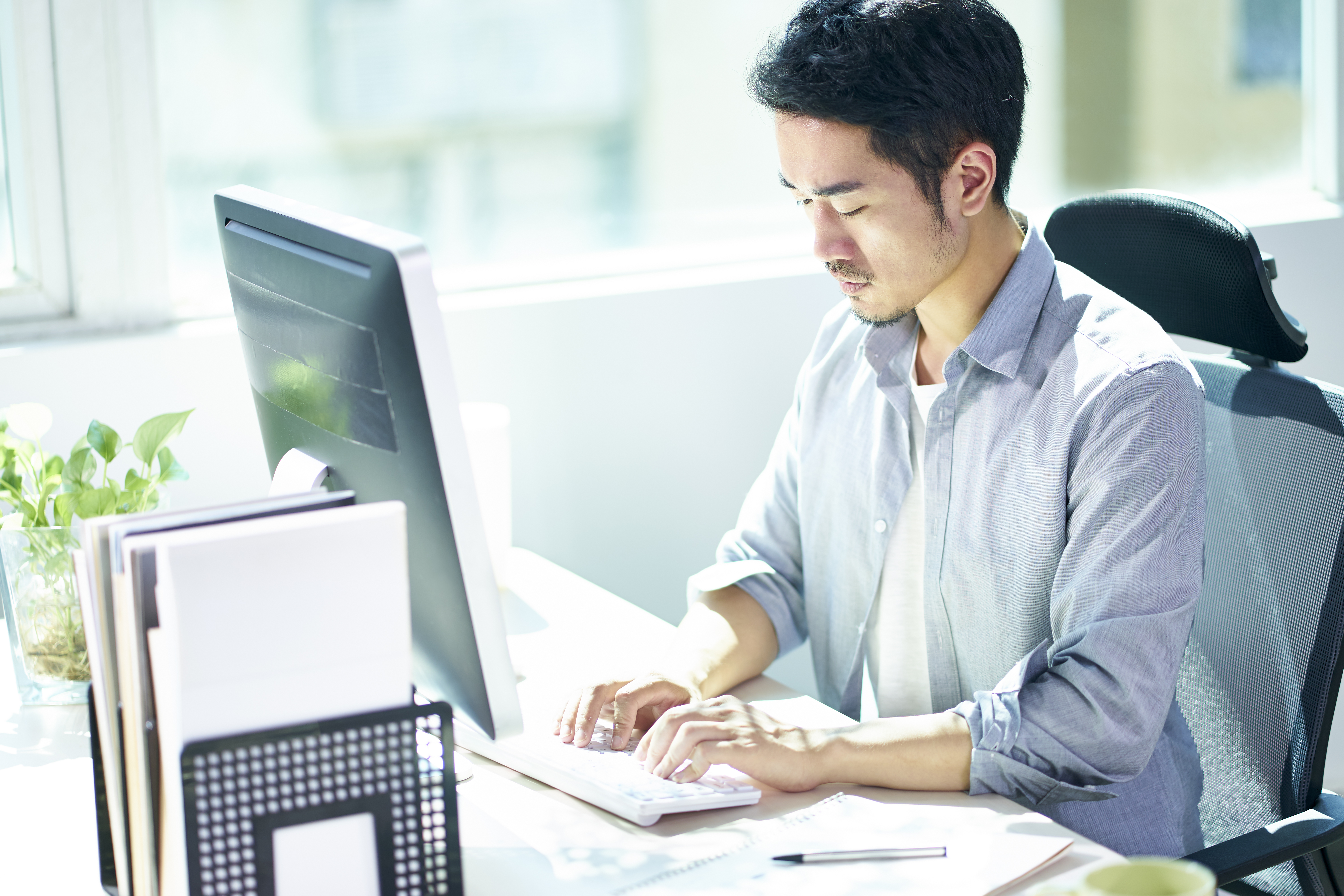 high angle view of a young asian businessman entrepreneur working in office using desktop computer.