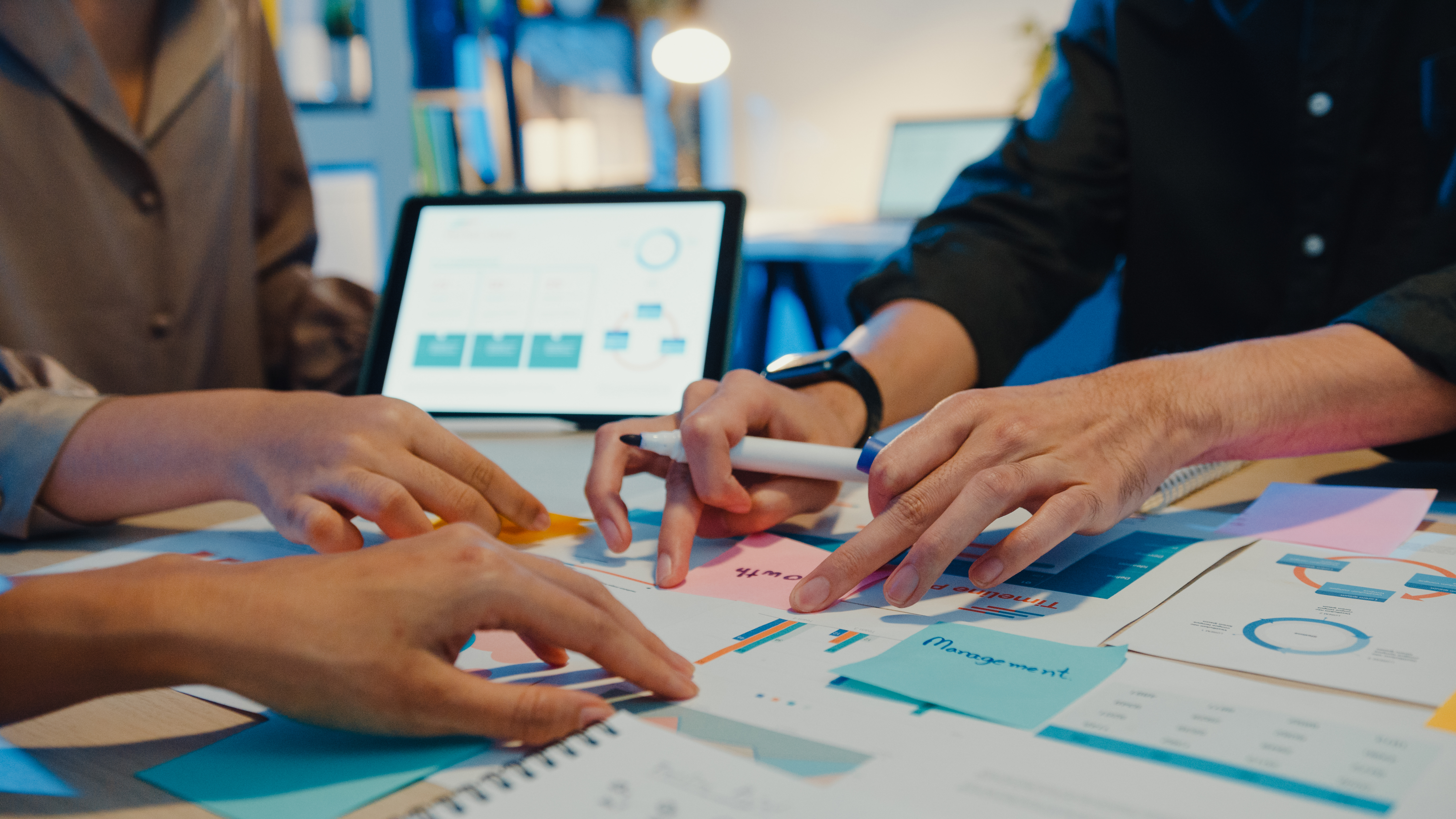 Group of Asia young creative people in smart casual wear discussing business brainstorming meeting ideas mobile application software design project in modern night office. Coworker teamwork concept.